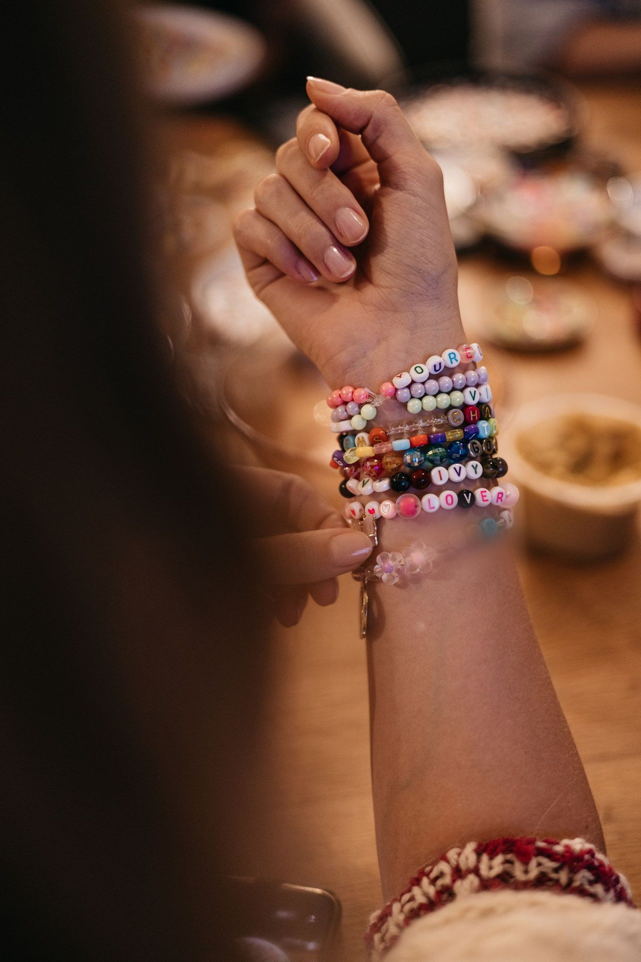 A wrist stacked with colorful word-bead bracelets