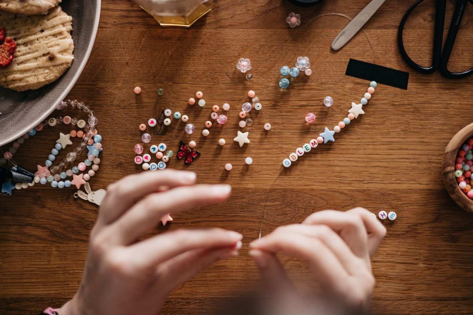Hands stringing letter beads onto a bracelet